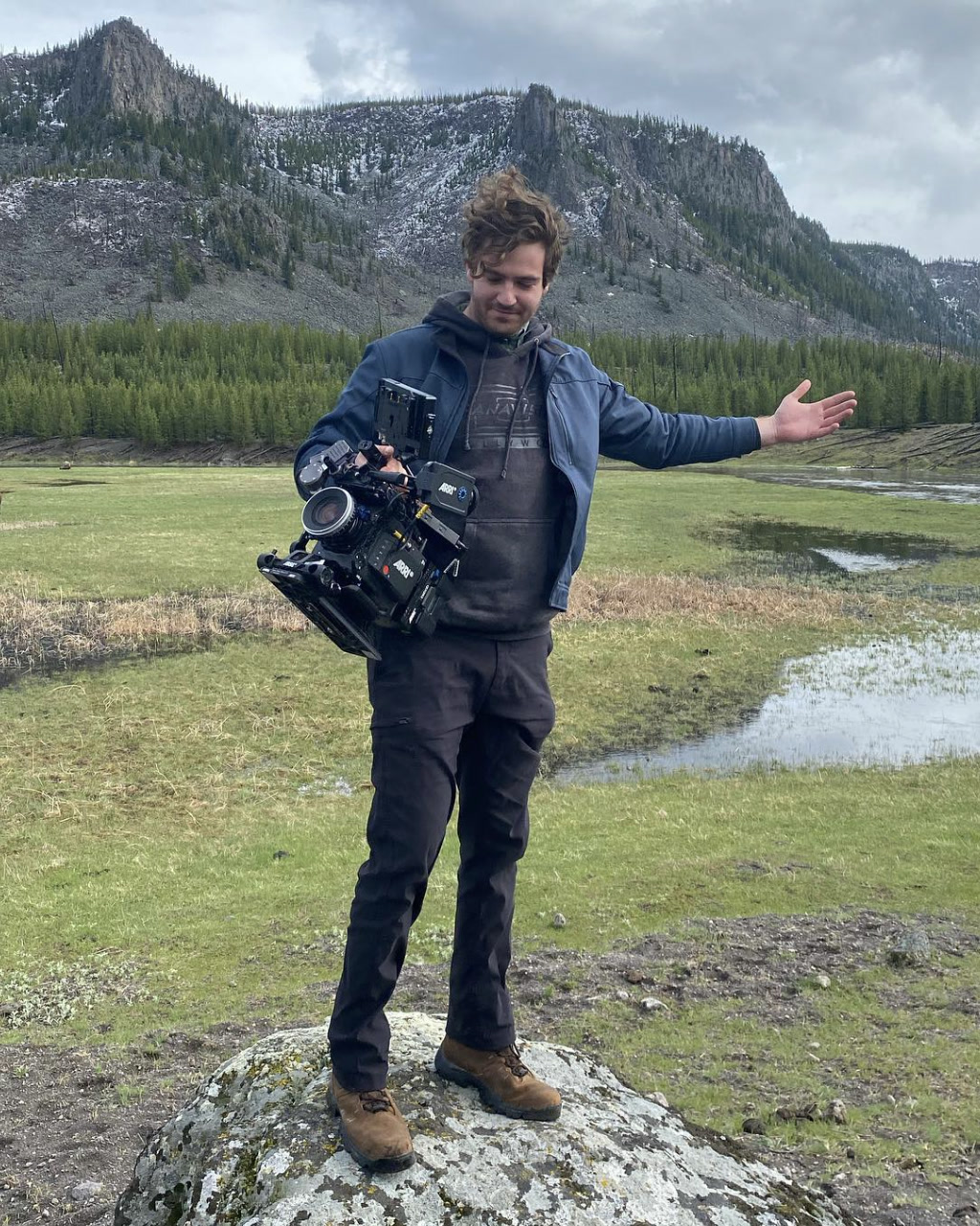 Adam Linssen holding a cinema camera on location in the mountains