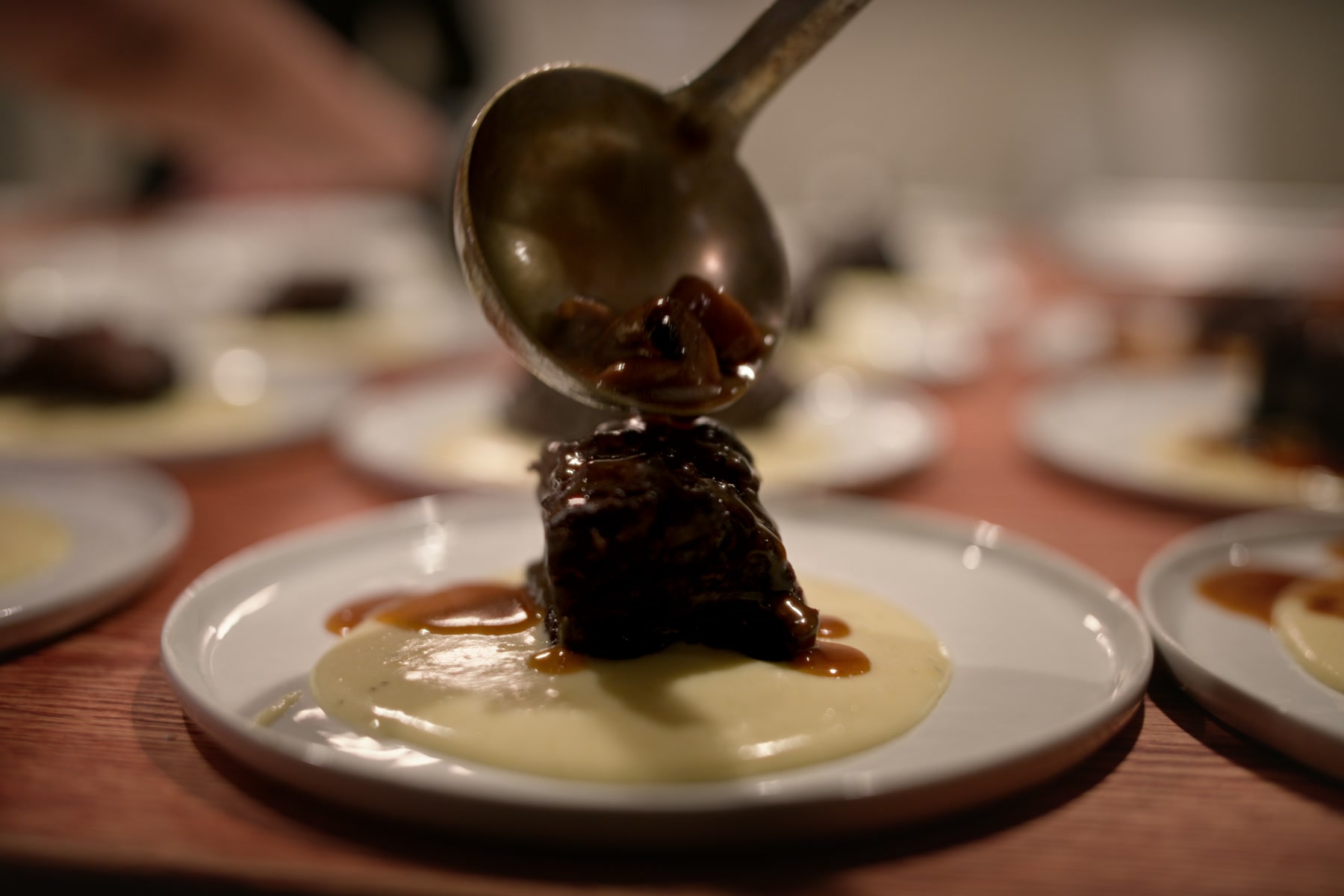 Sauce being spooned over a plated course