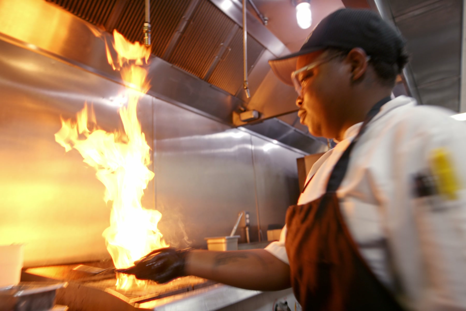A Kitchens for Good cook working over a burst of flame
