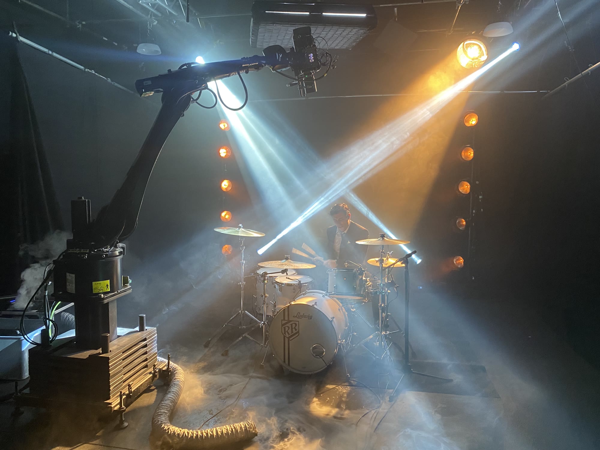 A camera crane filming a Ludwig drummer through blue and amber stage light