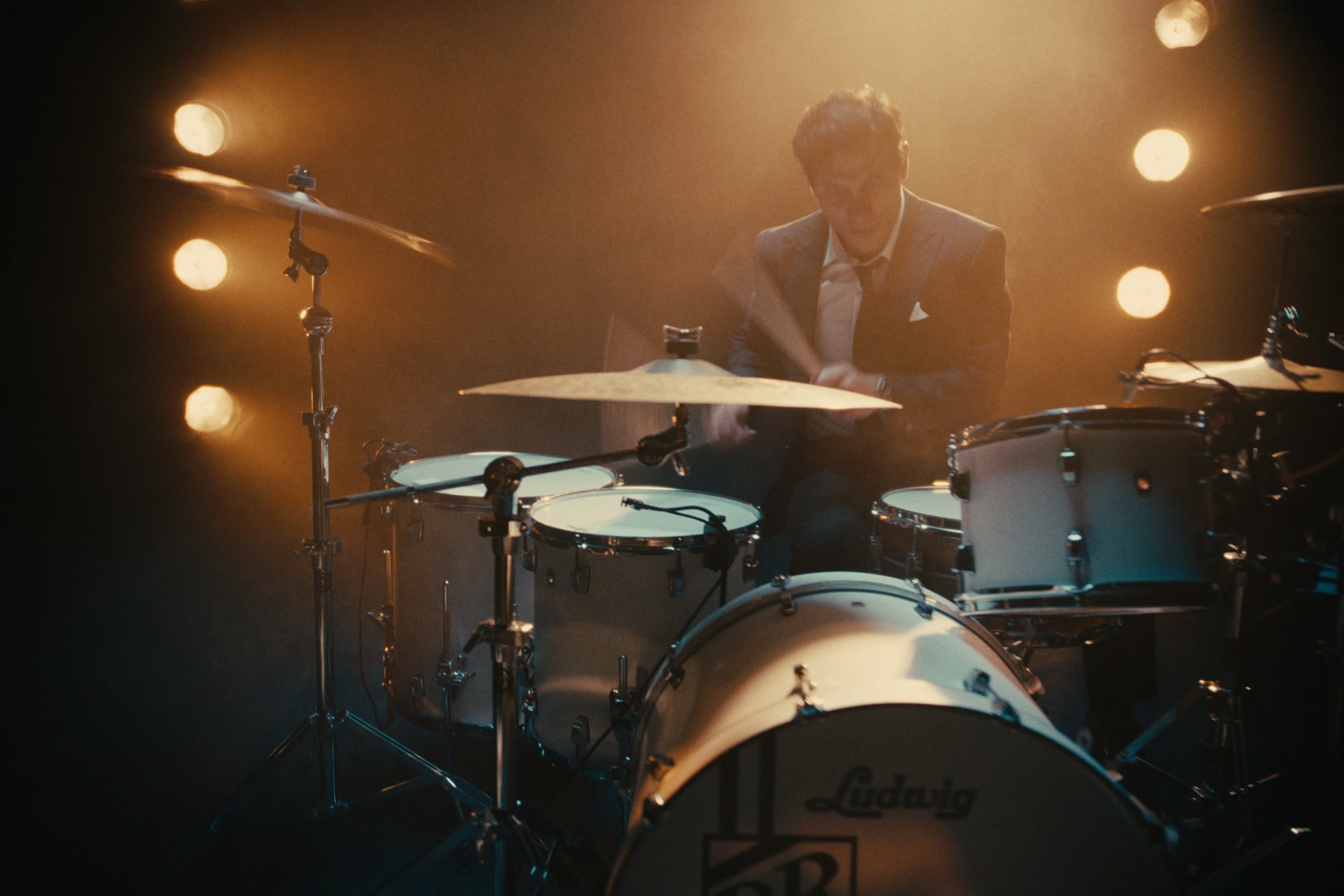 A drummer performing in warm stage light